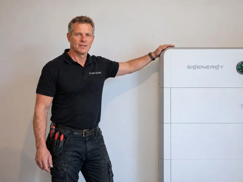 Installateur van Durahome naast een geplaatste thuisbatterij